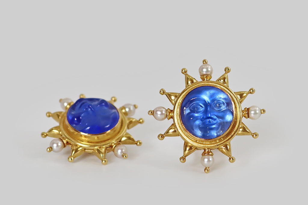 Antique Jewelry Portland, Vintage Jewelry Portland , Antique Engagement Rings | Poor Mouchette | A striking pair of large, late-vintage, Elizabeth Locke earrings, modeled in 18k yellow gold, whose central elements are a pair of blue, venetian-glass sun faces. These faces are smiling, apple-cheeked, and they have a deep, ethereal glow, thanks to the mother of pearl discs that lay behind them. Heavy borders, decorated with chubby, triangular rays, surmount our shining faces, and each halo of rays 