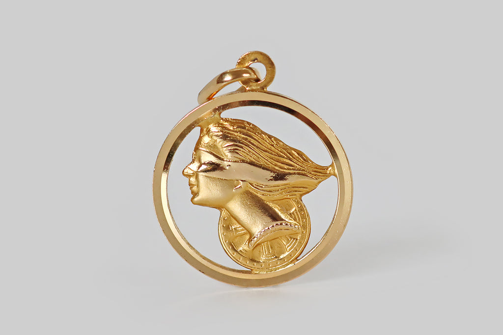 Poor Mouchette | Curated Antique Jewelry, Vintage Jewelry & Engagement Rings | Portland, Oregon | A vintage pendant, modeled in 18k yellow gold, featuring the bust of the Roman Goddess Fortuna and her wheel of fortune. Dea Fortuna is depicted, here, as a blindfolded woman with long, flowing hair⁠— she wears a carefree expression. The wheel of fortune is situated behind her, and a broad, circular frame encircles them both. This pendant has lovely dimensionality and depth. Both sides are fully finished
