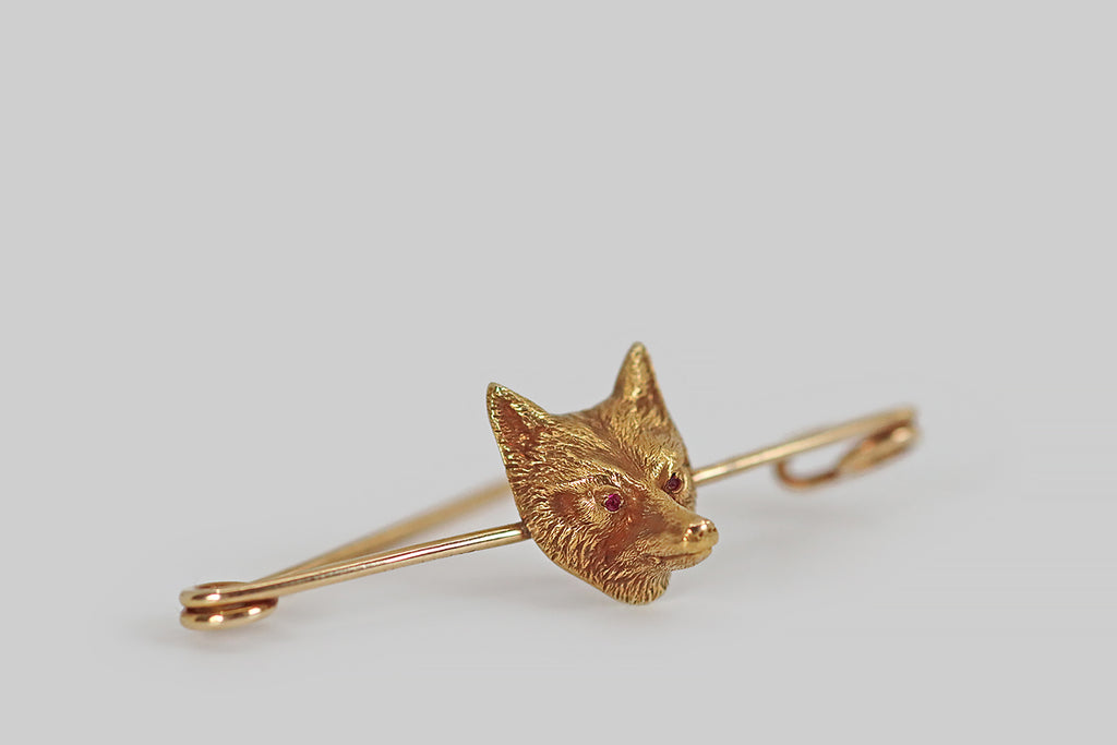 Poor Mouchette | Curated Antique Jewelry, Vintage Jewelry & Engagement Rings |A charming vintage stock pin, modeled in 14k yellow gold, by Cartier. This pin is features a beautifully-carved three dimensional fox mask. This fox is expressive and finely detailed, with naturalistic fur and faceted ruby eyes. The fox mask is welded to the centermost point of the stock pin. A stock tie is part of traditional equestrian dress.