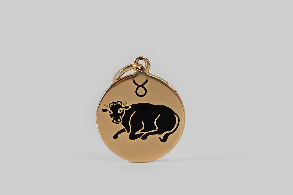Antique Jewelry Portland, Vintage Jewelry Portland , Antique Engagement Rings | Poor Mouchette | A petite vintage zodiac charm, modeled in 14k yellow gold, by the Richardson Mfg. Co. This little disc shaped charm is decorated with a gentle bull, in black and off-white enamel— he lies in repose beneath Taurus's astrological glyph. We love the posture of the bull here, calling to mind the down-to-earth gentleness and patience associated with this sign