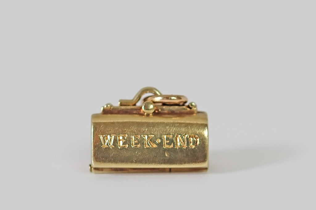 Antique Jewelry Portland, Vintage Jewelry Portland , Antique Engagement Rings | Poor Mouchette | A dainty, vintage charm, modeled as a weekend bag, by the well-known makers Sloan & Co., in 14k yellow gold. This get-away bag opens to reveal a puffy dress and bloomers, hanging inside— the miniature frock is enameled in pink and white, with black piping and a tiny black floral detail at the neck, and the little bloomers are made to match!