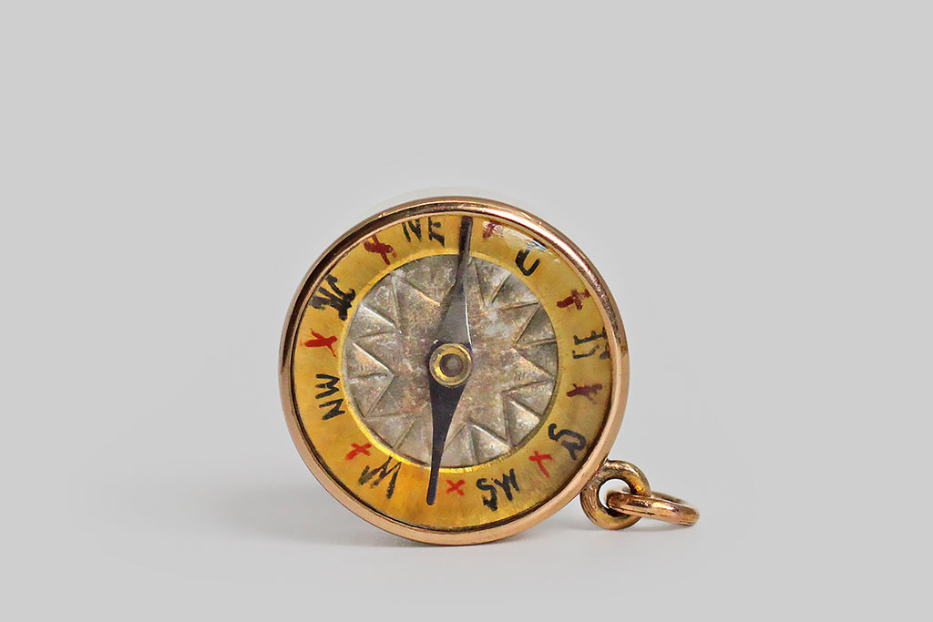 Poor Mouchette | Curated Antique Jewelry, Vintage Jewelry & Engagement Rings | Portland, Oregon | An unusual, working, Victorian-era compass fob, modeled in 14k yellow gold. This wonderful old compass features an ornate face, with a silvery, star-like center; its cardinal and inter-cardinal directions are hand-painted on the compass's gold rim, in blue, and these blue letters are separated by red "by" marks. The compass's needle is iridescent navy blue