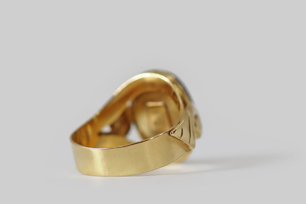 Antique Jewelry Portland, Vintage Jewelry Portland , Antique Engagement Rings | Poor Mouchette | A striking, late-century, Italian, lapis lazuli ring, modeled in 14k yellow gold, whose shoulders are decorated with a pair of voluptuous spirals. These spiral forms are "lifted" off the ring shank— they have soft, curved edges, and they terminate in a series of wing-like bars or hashes.