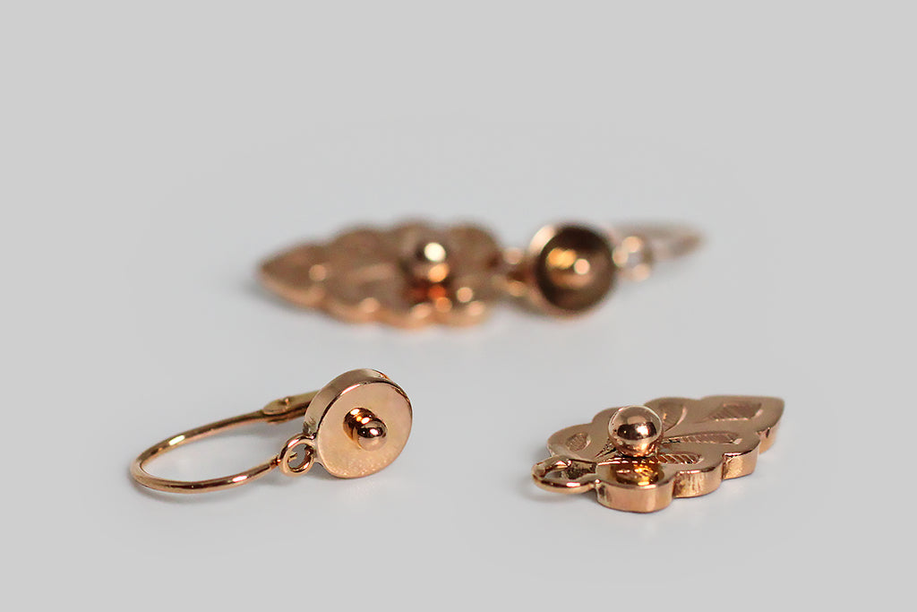 A dainty pair of antique, 18k rose gold, day and night earrings, whose drops are modeled as shapely leaves, most closely resembling the leaves of the Swedish White Beam tree. These feather-weight, French-made earrings have small, round, dormeuse-style tops, with back-to-front threading, hinged earwires. Their delicate, hand-engraved, leaf-form drops 