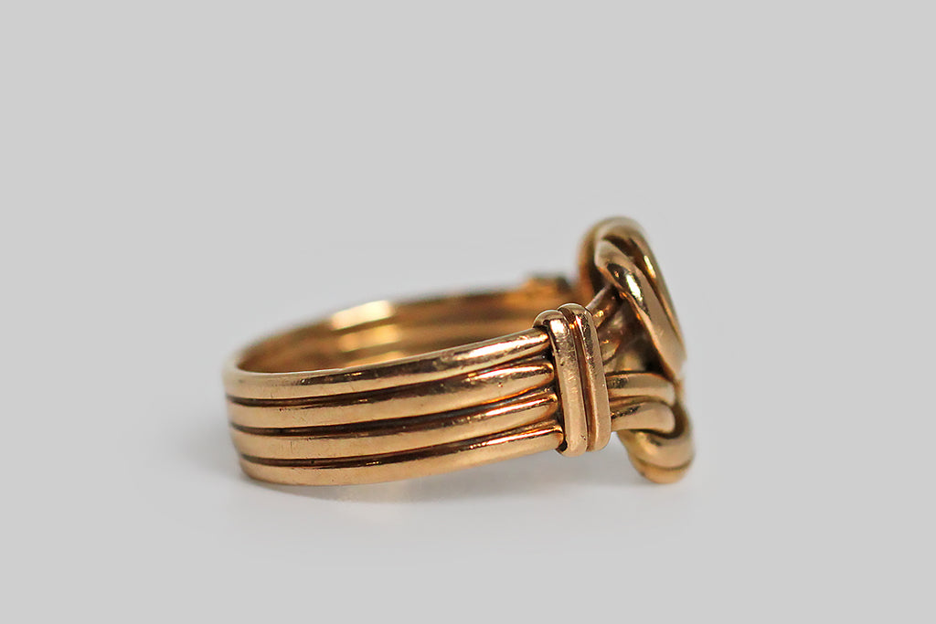 A striking Victorian-era wide band ring, modeled in 18k rosy yellow gold, whose face is a pair of sailor’s reef knots, laid one atop the other. These lovely, sinuous knots are each “tied” using pairs of gold wires, and these wires come together in a stack of four to form the ring shank. They are decoratively bound, with vertical straps, at the ring’s shoulders. Knot motifs from this era symbolized loyalty, fidelity, and the strength of a bond. This ring is fully hallmarked for Sheffield, and the year 1855.