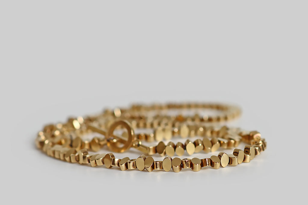 Poor Mouchette | Curated Antique Jewelry, Vintage Jewelry & Engagement Rings | Portland, Oregon | A very cool, late-vintage, 18k yellow gold necklace, composed of hand-finished (filed and polished), navette-shaped beads. These individually cast beads are plump, with flat faces, straight sides, and gently rounded points— they spin freely on their slender cable, creating subtle, shining texture and illusory variation in form.
