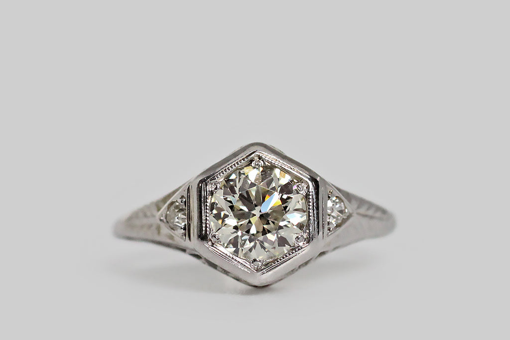 Poor Mouchette | Curated Antique Jewelry, Vintage Jewelry & Engagement Rings | Portland, Oregon | An elegant, Art Deco era engagement ring, modeled in 18k white gold, whose primary gem is a .96 carat old European cut diamond (K, VVS). This soulful, hand-cut diamond is bead-set into the ring's hexagonal face, where it is flanked by two smaller, old mine cut diamonds— these chunky supporters rest in pennant-shaped seats to the East and West.