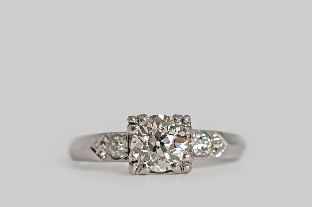 Poor Mouchette | Curated Antique Jewelry, Vintage Jewelry & Engagement Rings | Portland, Oregon | A lovely Art Deco era engagement ring, modeled in platinum, whose primary gem is a .69 carat old European cut diamond (GIA certified J/VS1). This vibrant, hand cut diamond is mounted in a low-profile basket setting, where four, clover-like, three-lobed prongs hold it securely in place. A pair of smaller, chunky, old-cut diamonds decorate the ring's shoulders, where they are bead-set into pennant-shaped seats.