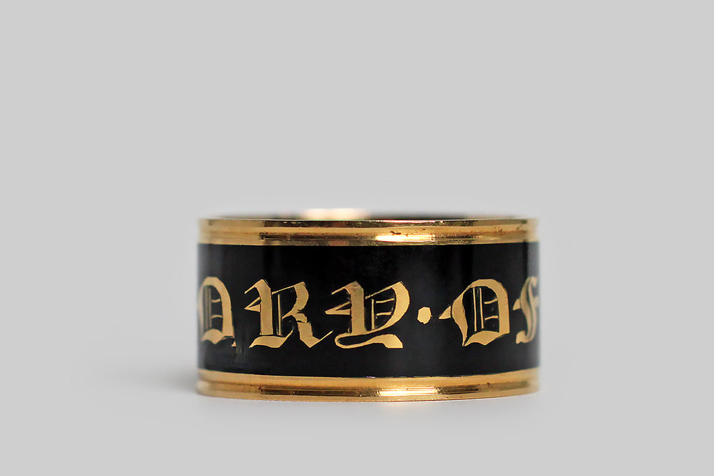Poor Mouchette | Curated Antique Jewelry, Vintage Jewelry & Engagement Rings | Portland, Oregon | A beautiful, Georgian-era, wide band ring, modeled in 18k gold and decorated with black enamel. This broad, flat mourning band was made in memory of George Moody, and it is dated for the year 1818. This has a very subtle ribbed detail, at the lip, but its striking, clean lines are otherwise uninterrupted. The band's smooth, enameled face reads “in memory of,” in bold gothic script.