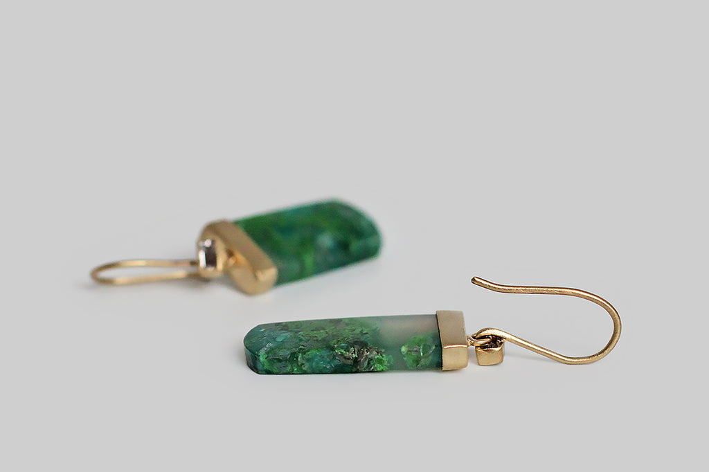 Brilliant, blue and green, tongue-shaped chrysocolla in quartz cabochons dangle beneath a bright pair of baguette-cut white diamonds. The diamonds are mounted in hand fabricated bezels, which are rectangular and subtly organic in form. The chrysocolla in quartz gemstones contain vibrant, mossy, blue and green forms, that read like tiny, captive otherworlds