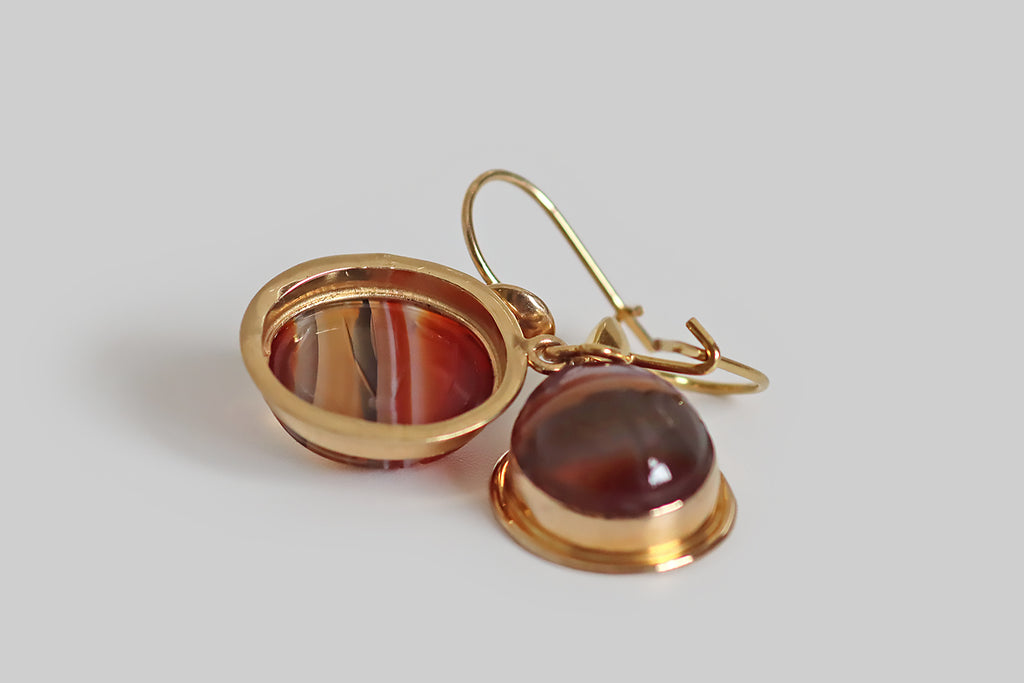 Antique Jewelry Portland, Vintage Jewelry Portland , Antique Engagement Rings | Poor Mouchette | A lovely pair of vintage dangling earrings, modeled in 14k yellow gold and set with carved banded agate cabochons. These oval cabochons have traditional carved details that transform them into scarab beetle amulets. Our agate scarabs are transparent and beautifully figured with red, orange, and black horizontal bands