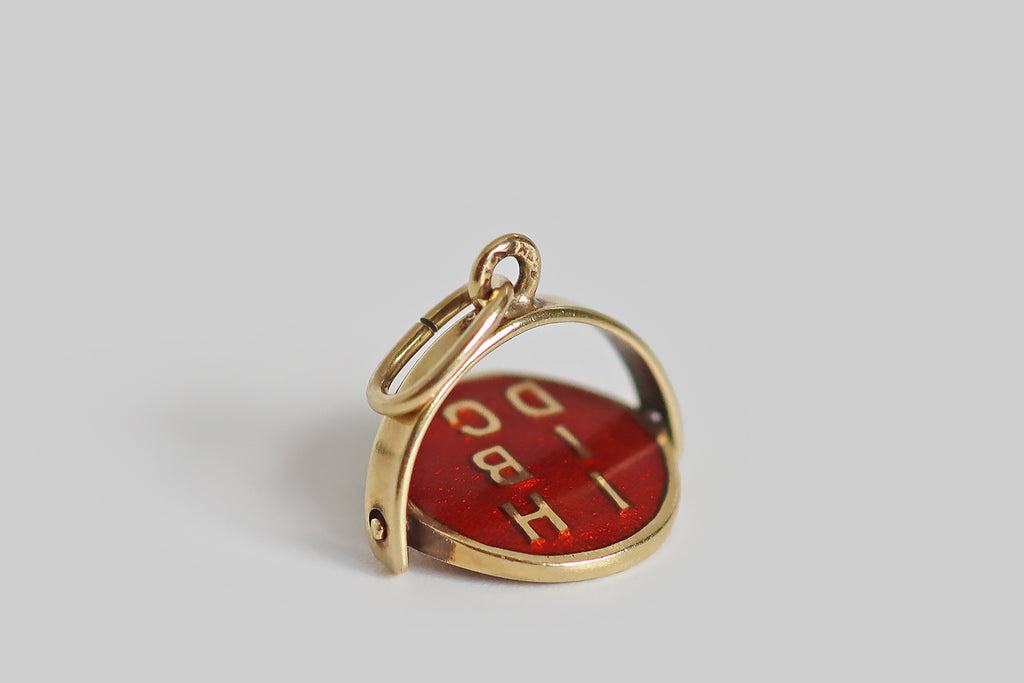 Antique Jewelry Portland, Vintage Jewelry Portland , Antique Engagement Rings | Poor Mouchette | A wonderful, early-20th-century enameled spinner charm, modeled in 14k yellow gold, whose central disc spins freely inside a stirrup-shaped "frame." This disc is decorated with bright red guilloche enamel. Gold letters from the phrase "ich liebe dich"