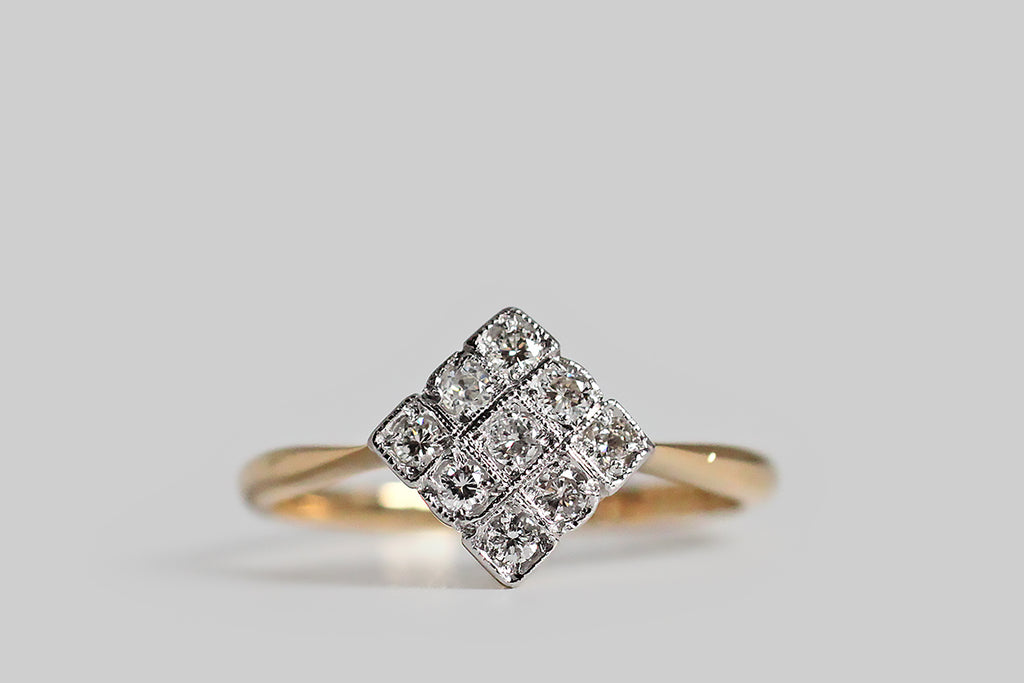 Poor Mouchette | Curated Antique Jewelry, Vintage Jewelry & Engagement Rings | Portland, Oregon | A charming, Art Deco era, diamond cluster ring, modeled in 18k yellow gold and platinum, with a diamond-shaped face. This elegant, low-profile ring is set with nine, sparkling, transitional cut diamonds— each of these gems is bead set into a square seat. These little diamond seats are crisp and distinct in the borderless ring face. They are separated by sparkling milgrain edges