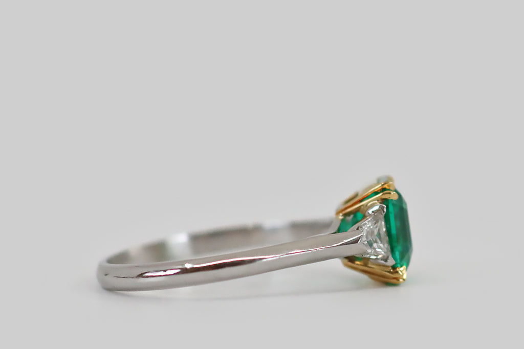 Antique Jewelry Portland, Vintage Jewelry Portland , Antique Engagement Rings | Poor Mouchette | An elegant Art Deco era engagement ring, modeled in platinum and 18k yellow gold, whose primary gem is an especially fine Colombian emerald (approx 1.9 carats). This square, step cut emerald has that most covetable, vivid, deep-bluish-green hue and remarkable transparency— it glows atop the ring's face, where it rests in a yellow gold basket.