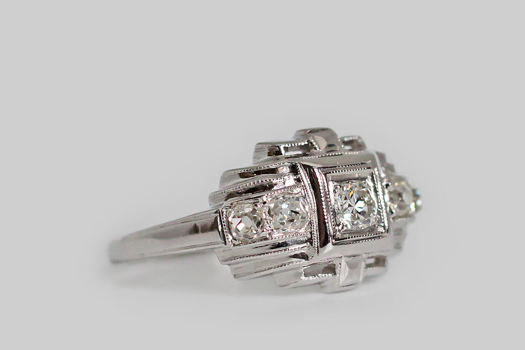 A charming, Art Deco era, five-stone engagement ring, modeled in platinum and set with approx .30 carats of lovely, old cut diamonds. This geometrically-inclined ring calls to mind a small, glittering temple (temple of your love perhaps!). The central transitional cut diamond weighs approx .10 carats