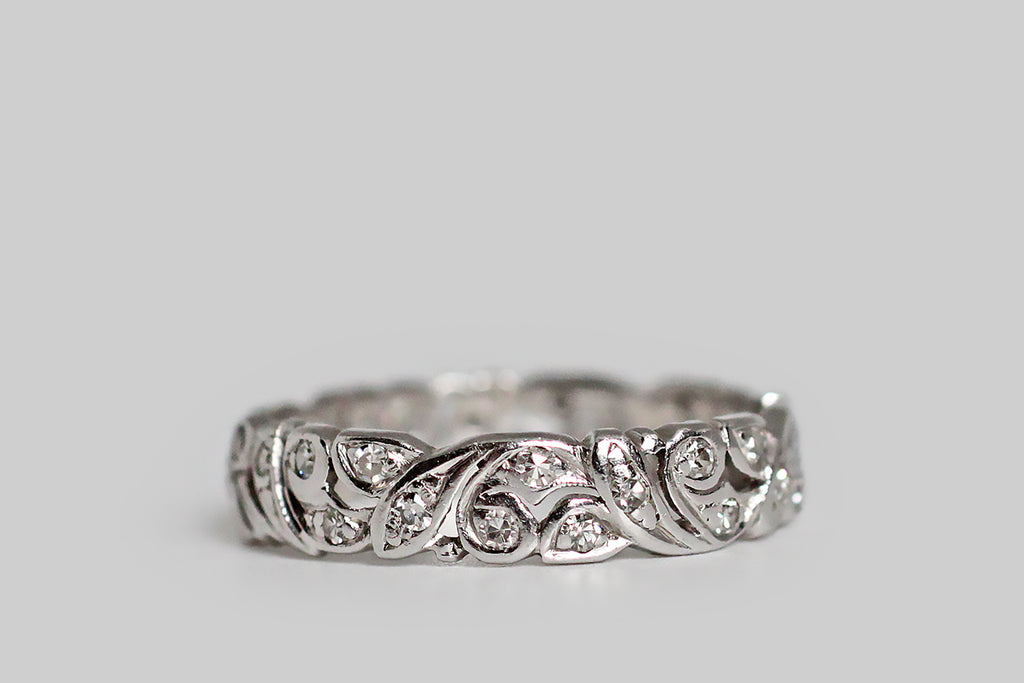 Poor Mouchette | Curated Antique Jewelry, Vintage Jewelry & Engagement Rings | Portland, Oregon | A lovely Art Deco era wedding band, modeled in platinum, with Art Nouveau sensibilities. This ring is hand pierced and its design is populated by various folate forms that bend gently, and scroll, and lay fluidly together. Each element of this leafy, hand-pierced puzzle is bead-set with a small, sparkling, single-cut diamond 