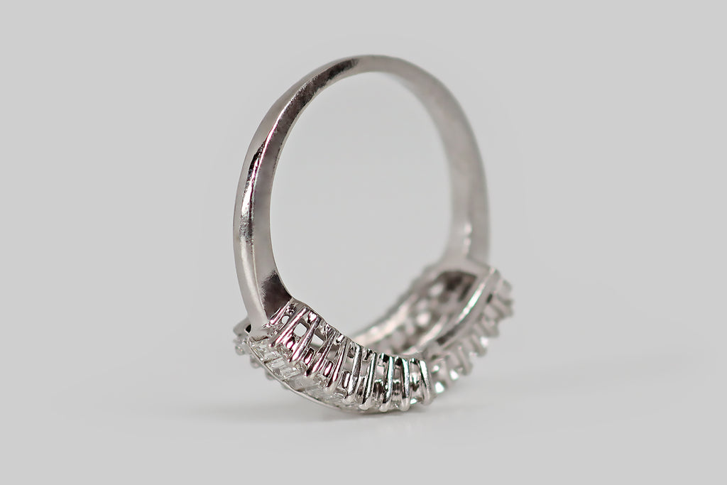 Antique Jewelry Portland, Vintage Jewelry Portland , Antique Engagement Rings | Poor Mouchette | A striking vintage cluster ring, modeled in platinum, whose face is decorated with three ribbon-like rows of beautiful baguette cut diamonds. These diamonds at arranged in an undulating manner— the central row of fifteen diamonds is framed by two "broken" rows of nine diamonds.