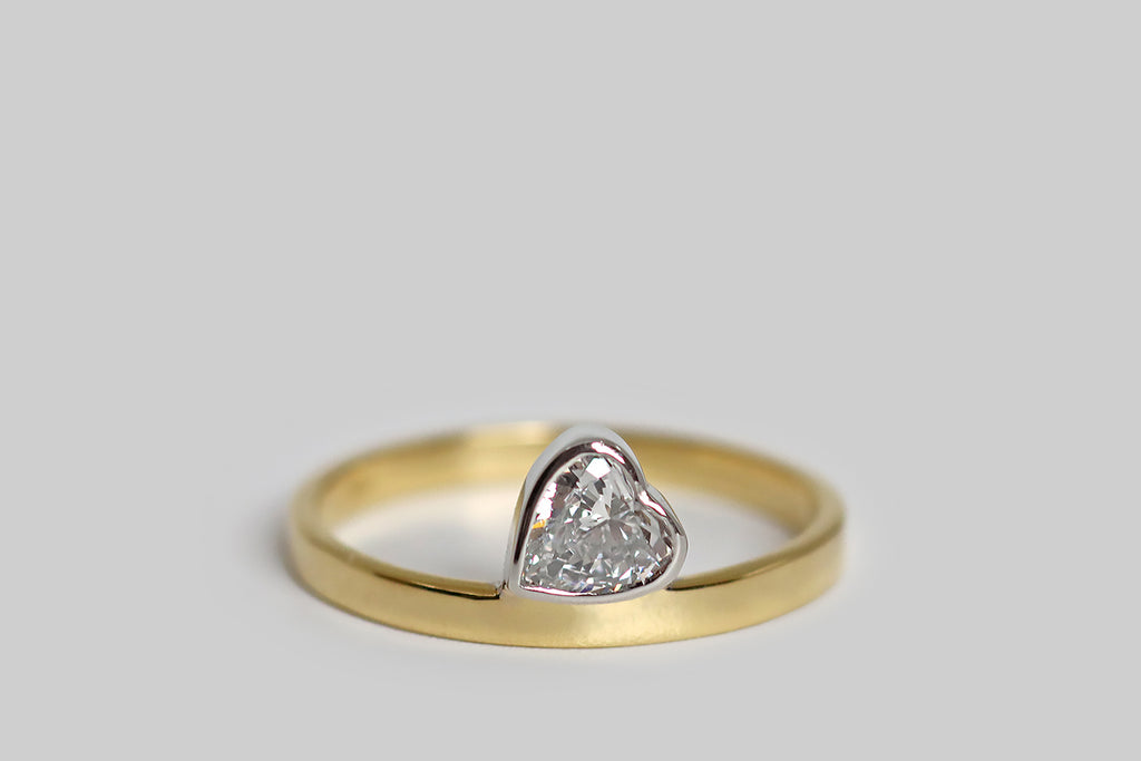 Poor Mouchette | Curated Antique Jewelry, Vintage Jewelry & Engagement Rings | Portland, Oregon | A playful, low-profile engagement ring, modeled in 18k yellow gold and platinum, whose gem is a vintage, heart-shaped diamond (.53 carats, F/G, VS). Our sparkling diamond heart is set in a platinum bezel— it seems to balance, precariously, atop the ring's slender, square shank. This ring is substantially made, with clean, crisp lines.