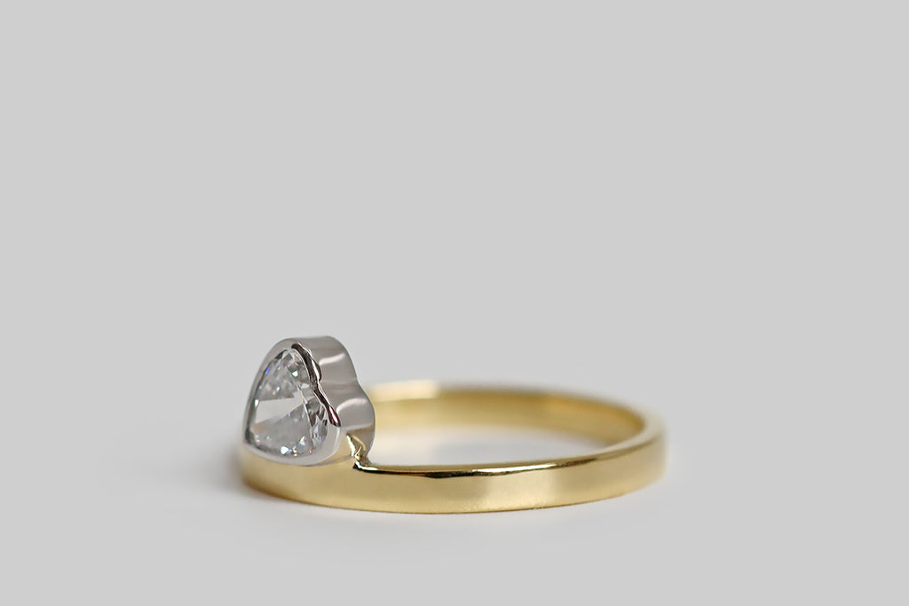 Poor Mouchette | Curated Antique Jewelry, Vintage Jewelry & Engagement Rings | Portland, Oregon | A playful, low-profile engagement ring, modeled in 18k yellow gold and platinum, whose gem is a vintage, heart-shaped diamond (.53 carats, F/G, VS). Our sparkling diamond heart is set in a platinum bezel— it seems to balance, precariously, atop the ring's slender, square shank. This ring is substantially made, with clean, crisp lines.