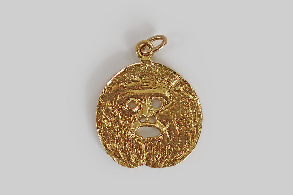 Poor Mouchette | Curated Antique Jewelry, Vintage Jewelry & Engagement Rings | Portland, Oregon | An unusual vintage pendant, modeled in 18k yellow gold, whose coin-like surface is sculpted with fine, varied, organic textures. The center of the pendant has been pierced to create a simple face, with an open mouth, which is meant to resemble Bocca Della Verità "The Mouth of Truth," a large, marble mask located in Rome, Italy.