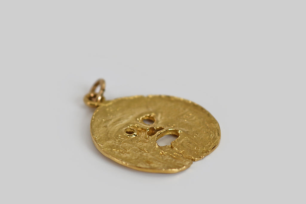 Poor Mouchette | Curated Antique Jewelry, Vintage Jewelry & Engagement Rings | Portland, Oregon | An unusual vintage pendant, modeled in 18k yellow gold, whose coin-like surface is sculpted with fine, varied, organic textures. The center of the pendant has been pierced to create a simple face, with an open mouth, which is meant to resemble Bocca Della Verità "The Mouth of Truth," a large, marble mask located in Rome, Italy.