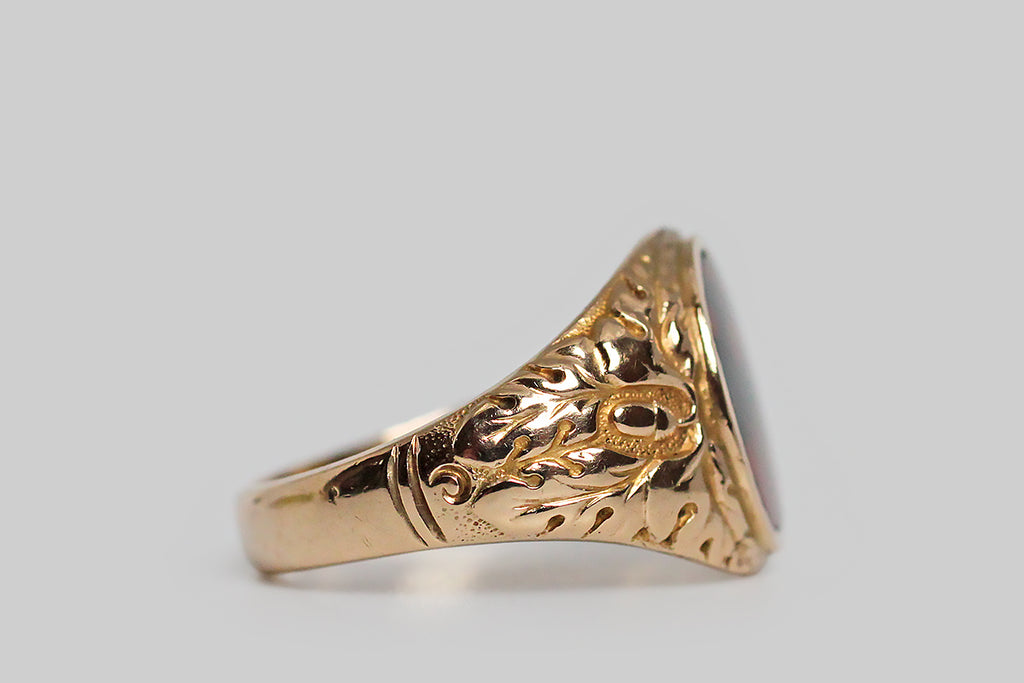 A striking, 1940s, bloodstone signet ring, modeled in 10k yellow gold, whose shoulders feature a deeply-carved decor of oak leaves and acorns. This carving is of very fine quality, with expressive lines, subtle variations, and a stippled ground that creates visual depth in the relief. Acorns symbolize growth and potential, while oak leaves stand for strength, endurance and fertility. Remember the old adage: all the wonder in a mighty oak grows from a single acorn.
