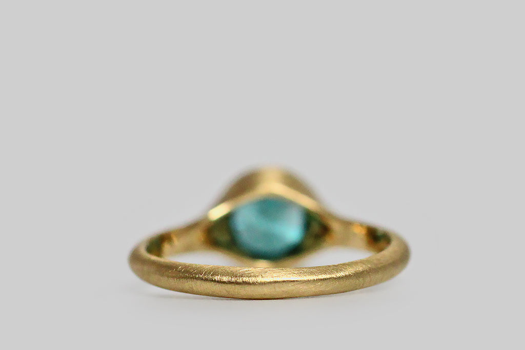 Vibrant and tranquil, a round, faceted, 2.2 carat, blue zircon gem lays nested, inside a thick-walled, organic bezel, which tapers seamlessly into its ring's integral shank. Zircon is an unusual gemstone that has the distinction of being the oldest mineral found on earth, at 4.4 billion years old— in the middle ages it was thought to induce sound sleep, and to drive away evil spirits. This blue zircon gem was originally mined and cut in the 1930s— its facets have been carefully refreshed by a local cutter. 