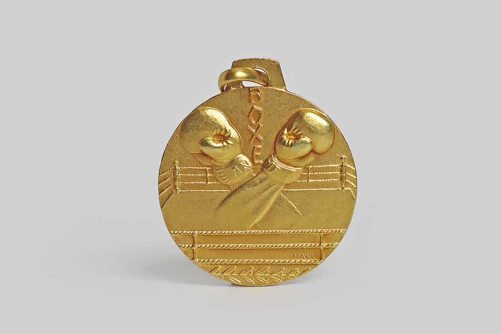 Poor Mouchette | Curated Antique Jewelry, Vintage Jewelry & Engagement Rings | Portland, Oregon | A very cool vintage medal, modeled in 18k yellow gold, by the Italian maker UnoAerre. This pendant medal features a highly-unusual, beautifully-carved motif of a boxing ring, at the center of which we find the crossed arms of two boxers, wearing boxing gloves, ready to begin their bout. 