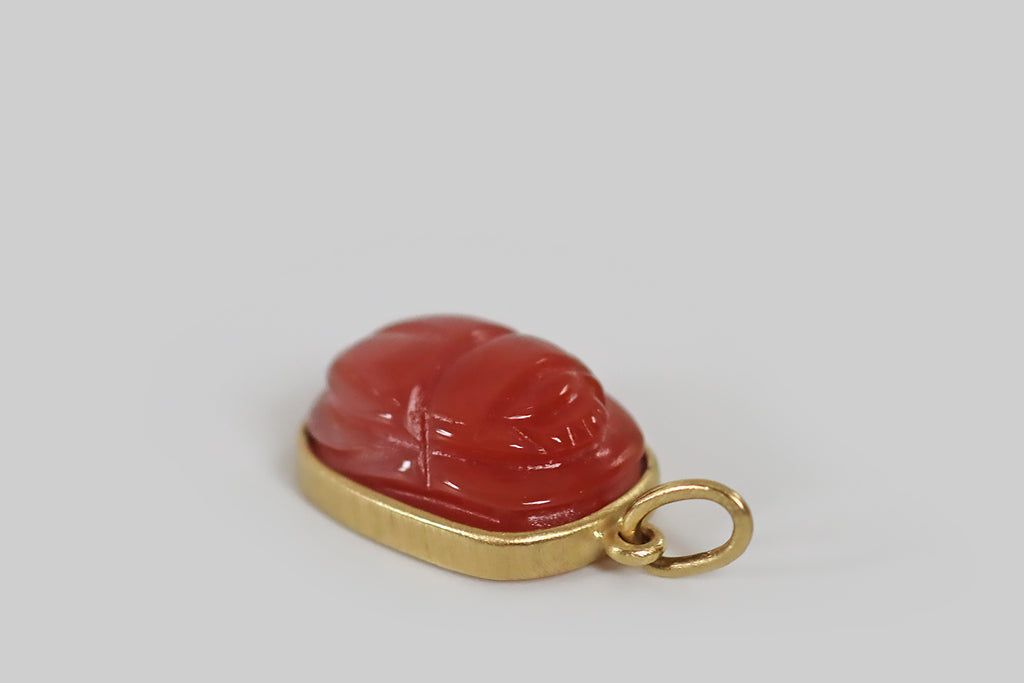 Antique Jewelry Portland, Vintage Jewelry Portland , Antique Engagement Rings | Poor Mouchette | A charming pendant, modeled in 18k yellow, that features a vintage carnelian cabochon, carved to represent a scarab beetle. This carnelian is softer and a bit rosier than usual, and the scarab carving is especially well-executed, with attractive proportions and polished edges— it is smooth, semi-translucent, and glowy!