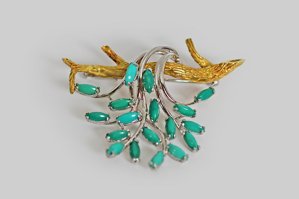 A serene and whimsical mid-twentieth-century brooch, made in 18k gold to recall a branch, draped with cascading foliage. The branch in this composition is modeled in vibrant yellow gold and is realistically textured; the foliate elements are small marquise-shaped chrysocolla cabochons— each of these gems (there are eighteen, in total) is set in a delicate, white gold four-prong basket setting.
