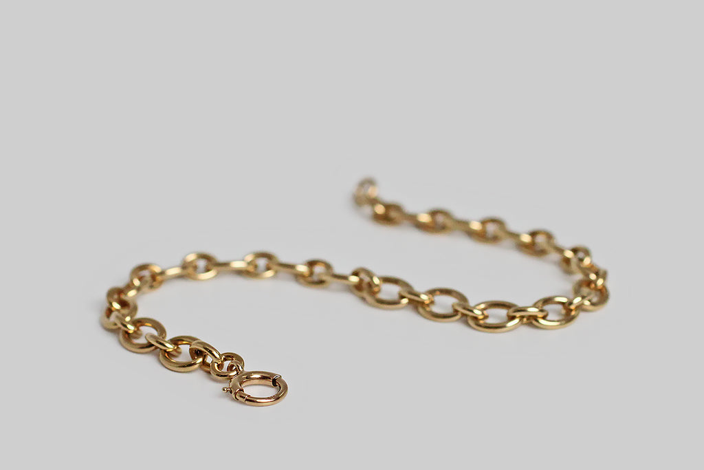 A weighty, mid twentieth century, 14k yellow gold cable link bracelet, comprised of long and short oval links. This bracelet is appealing for its minimalist design and beautiful, handmade construction. It has the soft, buttery glow that we love in vintage gold jewelry. This bracelet closes with a large bolt ring clasp. It makes a lovely, effortless statement, worn alone; it would also be a perfect foundation for a collection of charms.