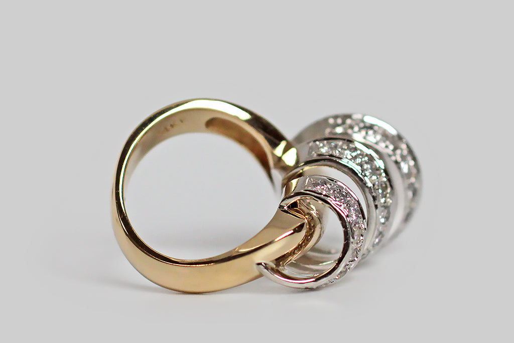A vintage modernist ring, modeled substantially in 14k gold, whose unusual figure can be compared to a diamond-encrusted cyclone. The ring head’s open, spiraling white gold form whorls around a weighty, diagonally-placed, yellow gold rod— the graduating white gold form is highly-dimensional and is enlivened by many bead-set white diamonds. 