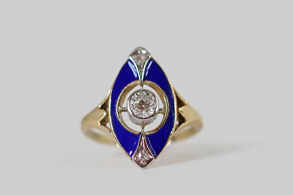 Poor Mouchette | Curated Antique Jewelry, Vintage Jewelry & Engagement Rings | Portland, Oregon | A charming Edwardian era ring, modeled in 14k gold, whose navette-shaped face is decorated with glassy, cobalt-blue enamel. This petite navette has a circular opening at its center, where a sparkling, 1/3 carat, old mine cut diamond rests in a "floating" platinum bezel. A pair of shapely, diamond-set, platinum forms accent the north and south points of the ring face, reading like plumes extending