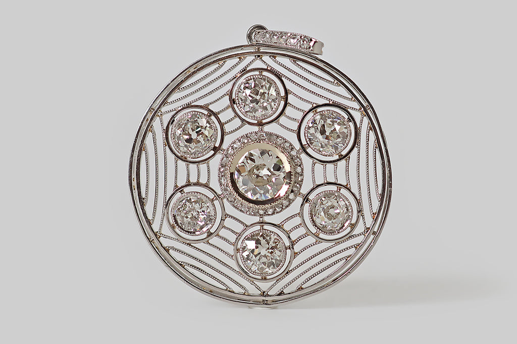 Antique Jewelry Portland, Vintage Jewelry Portland , Antique Engagement Rings | Poor Mouchette | A striking Art Deco era pendant, modeled in platinum, whose fine, hand-fabricated filigree forms a spider's web inside of the pendant's circular frame. Seven, sparkling old mine cut diamonds are "caught" in this web. The primary diamond is approx .93 carats— it rests in a mirror edge bezel, surrounded a halo of small rose cut diamonds.