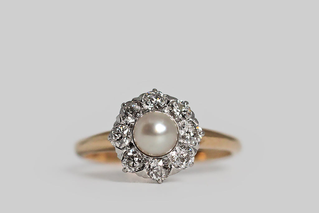 Poor Mouchette | Curated Antique Jewelry, Vintage Jewelry & Engagement Rings | Portland, Oregon | An especially winning example of a classic style, this Edwardian-era pearl and diamond halo ring, modeled in rosy 14k and platinum, has beautiful proportions! The ring’s central, luminous, champagne-white pearl is set in a fitted cup— it surrounded by a halo of eight, chunky, old European cut diamonds. These soulful, hand-cut diamonds are set into the ring's crownlike head