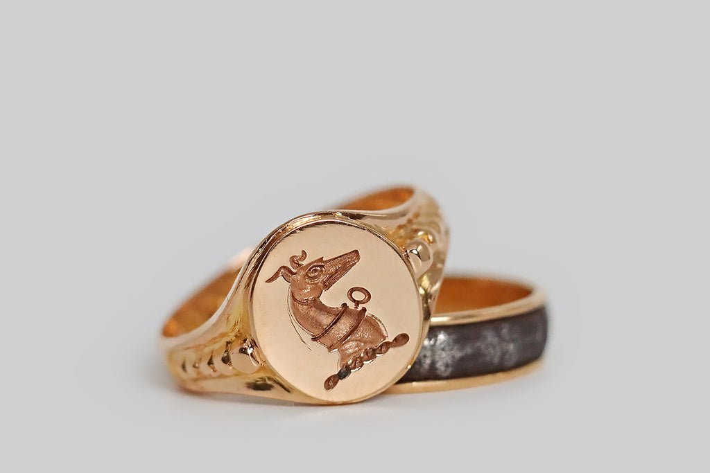 Poor Mouchette | Curated Antique Jewelry, Vintage Jewelry & Engagement Rings | Portland, Oregon | A weighty, Edwardian-era signet ring, modeled in 18k rose gold, featuring a beautifully-rendered greyhound intaglio. This dignified pup wears an alert expression; his ears are perked, and he sports a collar with a prominent bolt ring or key. The oval face of the ring is finished with a mirror polish— our canine friend's deep, stippled texture stands in contrast.
