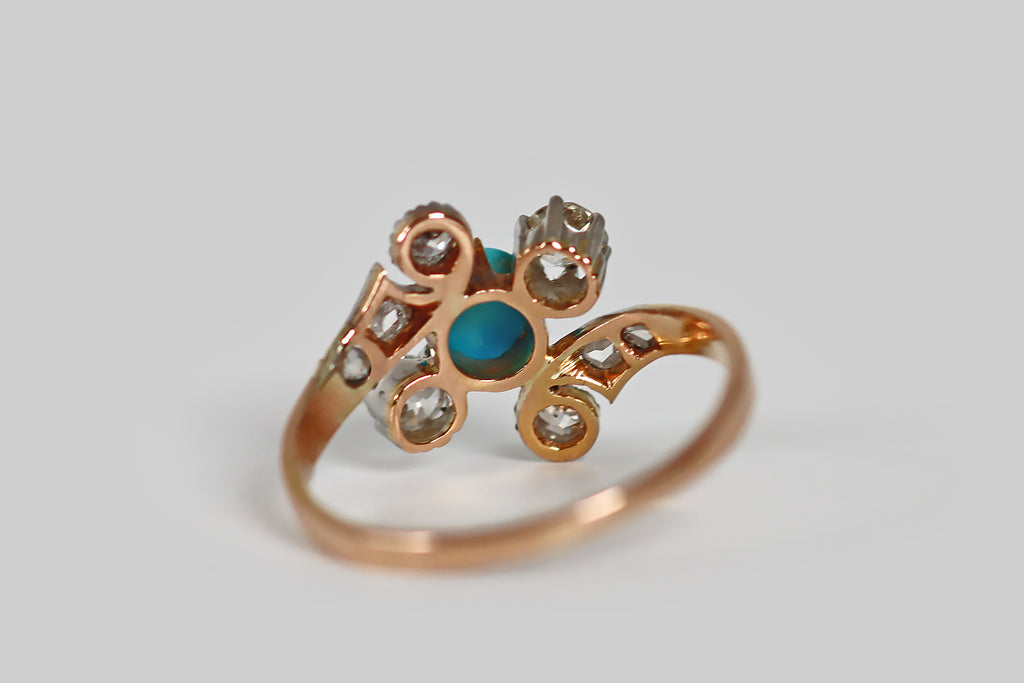 Antique Jewelry Portland, Vintage Jewelry Portland , Antique Engagement Rings | Poor Mouchette | A very sweet Victorian-era ring, modeled in 18k rose gold and platinum, whose bypass style shank cradles a diagonally-oriented, three-stone head. The ring's three primary stones (a bright-blue, oval, turquoise cabochon, and a pair of old European cut diamonds) are held in prong settings. The ring's curling shank features a pair of old European cut diamond