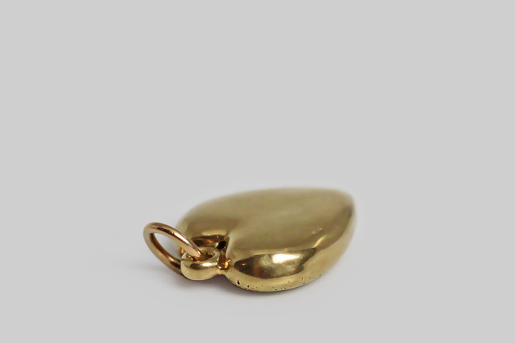 A darling, Art Deco era, heart-shaped harm, modeled in 14k yellow gold, and decorated with flowers in blue and white enamel. These little blossoms (lilies of the valley and forget me nots) sit atop the charm's finely-speckled, hand-textured surface. 
