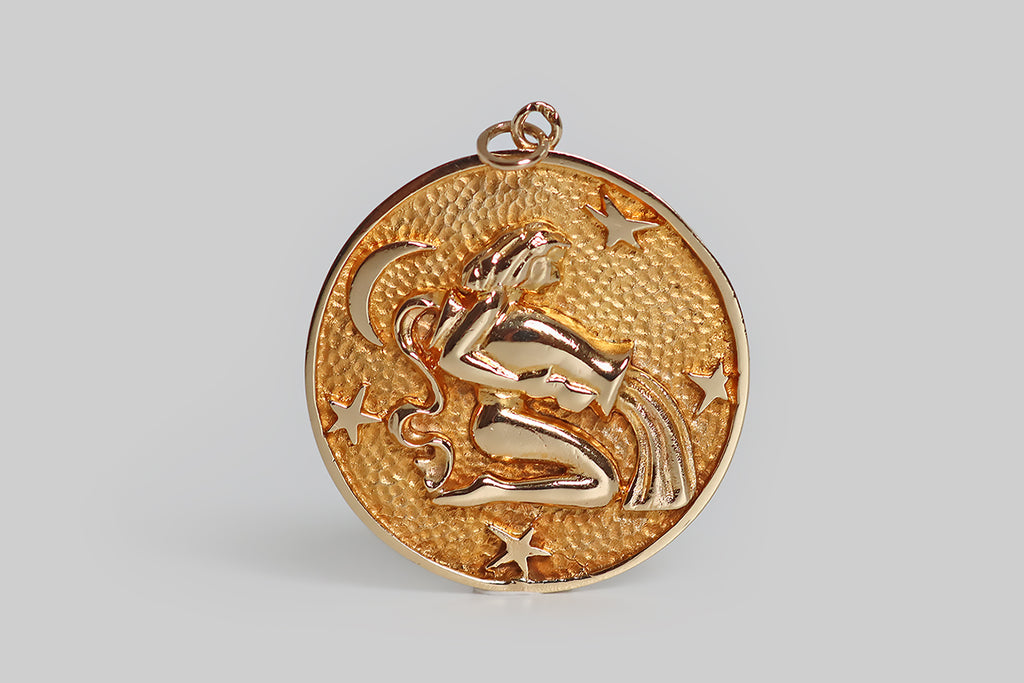 Poor Mouchette | Curated Antique Jewelry, Vintage Jewelry & Engagement Rings | Portland, Oregon | A very cool, extra-large, mid 20th century pendant, modeled in 14k yellow gold, whose subject is the water bearer, an image that represents the astrological sign Aquarius (January 20 - February 18). Our female water bearer has wavy, shoulder-length hair. Here, she kneels, in profile, surrounded by four stars and a crescent moon, pouring water from a vessel. 