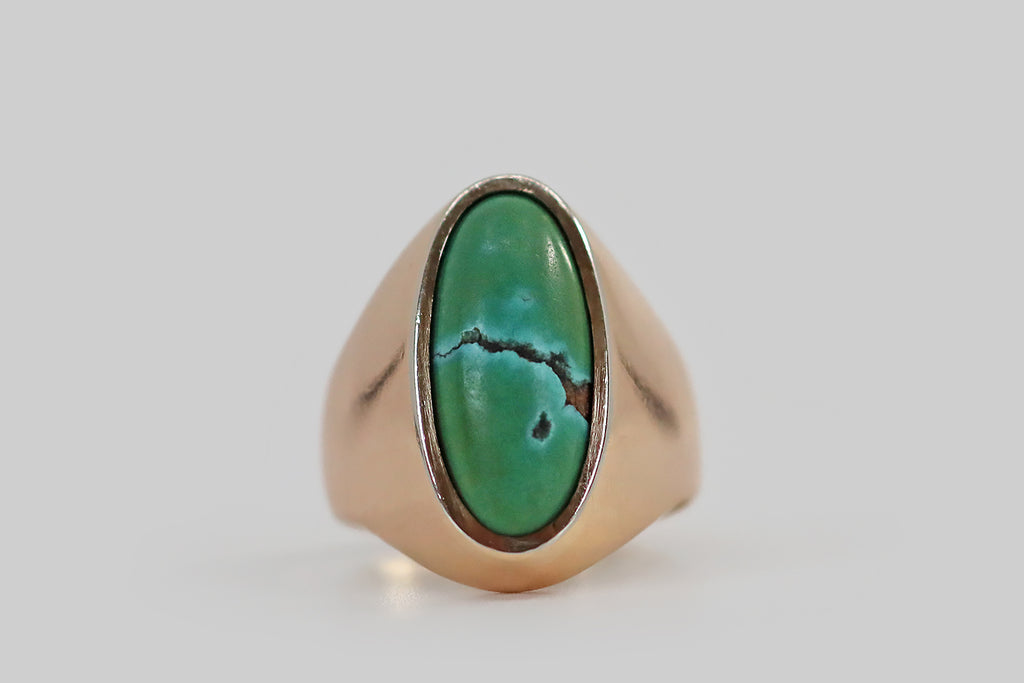 Antique Jewelry Portland, Vintage Jewelry Portland , Antique Engagement Rings | Poor Mouchette | A striking mid-twentieth-century ring, crafted in 18k rosy yellow gold, that features a beautifully-figured, bezel-set, long-oval turquoise cabochon. This vibrant, blue-green gem is bifurcated by fissure-like band of brown matrix. A sky-blue "highlight" appears at the edges of this matrix ridge— below it a pear-shaped spot of matrix hangs like a tear.