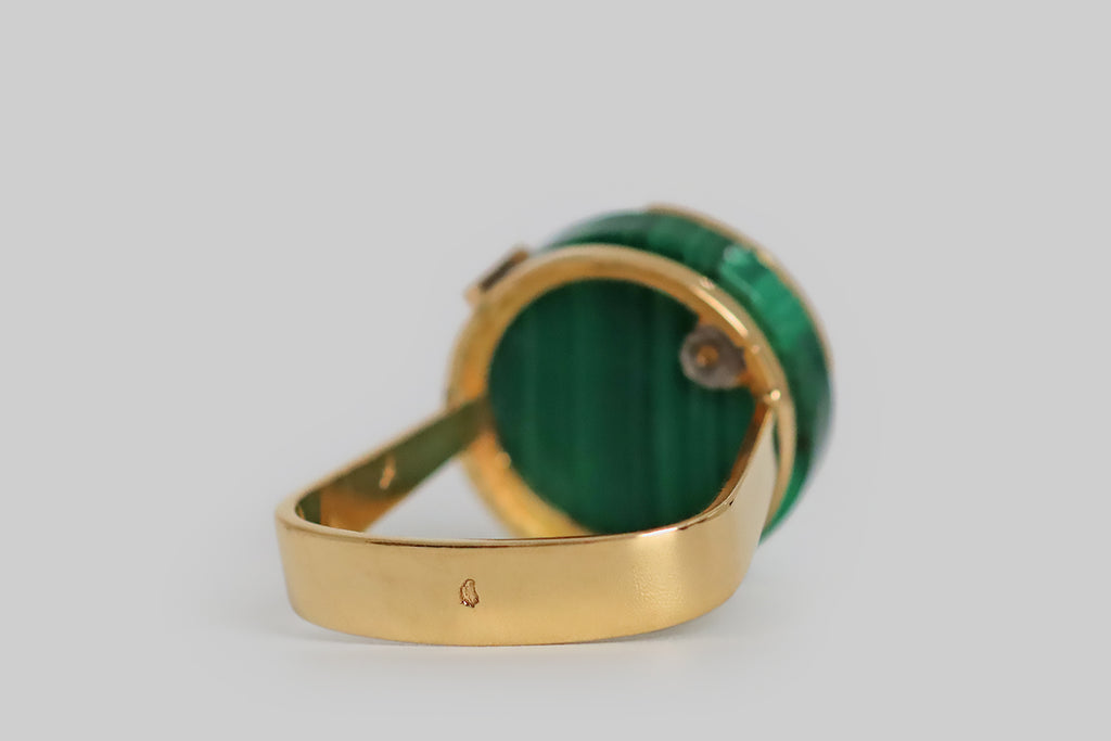 Poor Mouchette | Curated Antique Jewelry, Vintage Jewelry & Engagement Rings | Portland, Oregon | A clever, mid-20th-century, modernist ring, modeled in 18k yellow gold, whose face is set with a thick, circular malachite slab. This vivid green gem is beautifully figured with vertical stripes. It is held in a pair of angular prongs, and a high-polished, pie-slice-shaped gold sheet lays atop it, as if to signify one quarter of the whole.