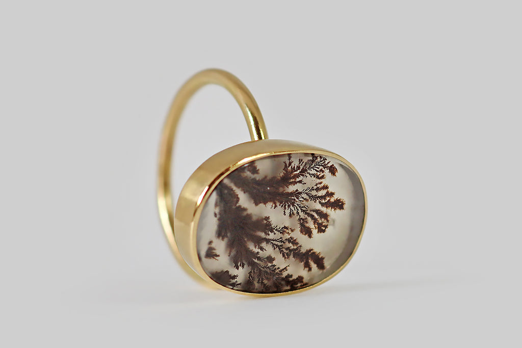 VPoor Mouchette | Curated Antique Jewelry, Vintage Jewelry & Engagement Rings | Portland, Oregon | A dendritic agate ring, fabricated in 18k yellow gold by the designer Gabriella Kiss. This gate has a serene presence— it is figured with feathery, red-brown plumes that appear frozen, mid-sway, inside its clear, chalcedony field. The agate is held in a smooth, low-profile, closed-back bezel that perches atop the ring’s slender, fully-round shank.