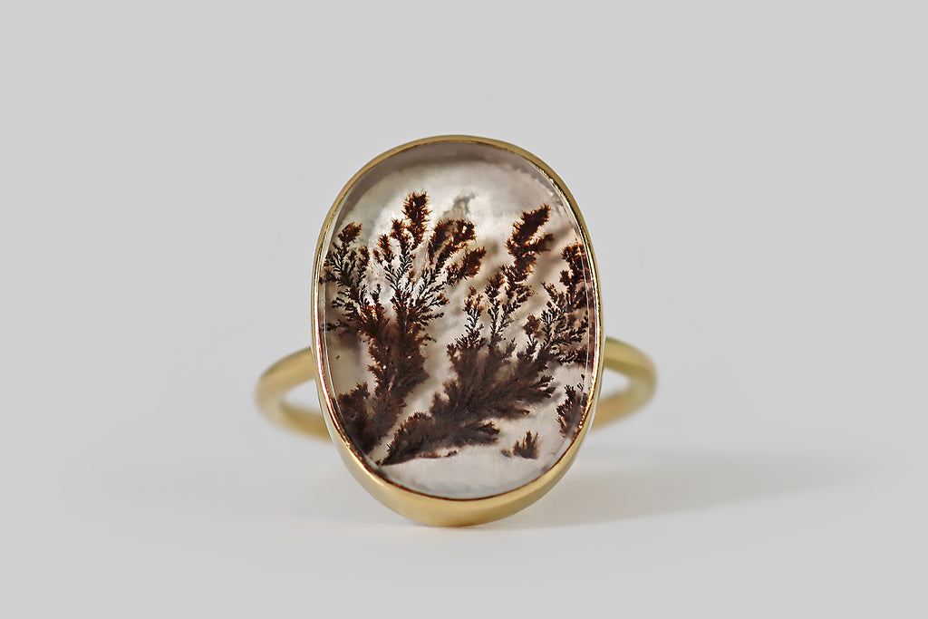 VPoor Mouchette | Curated Antique Jewelry, Vintage Jewelry & Engagement Rings | Portland, Oregon | A dendritic agate ring, fabricated in 18k yellow gold by the designer Gabriella Kiss. This gate has a serene presence— it is figured with feathery, red-brown plumes that appear frozen, mid-sway, inside its clear, chalcedony field. The agate is held in a smooth, low-profile, closed-back bezel that perches atop the ring’s slender, fully-round shank.