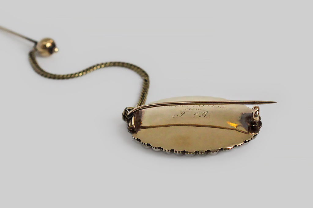 A sizable 19th century brooch, featuring two different locks of human hair (strawberry blond and silvering brunette), woven together and set beneath a beveled crystal. This plaited arrangement is encircled by an especially pretty natural pearl surround. The base of the brooch, and the many cut down collet settings are 15k yellow gold. This brooch was perhaps intended as a romantic gift for a sweetheart— its reverse is inscribed (in curling period script) "L.H. Bliss from J.B."