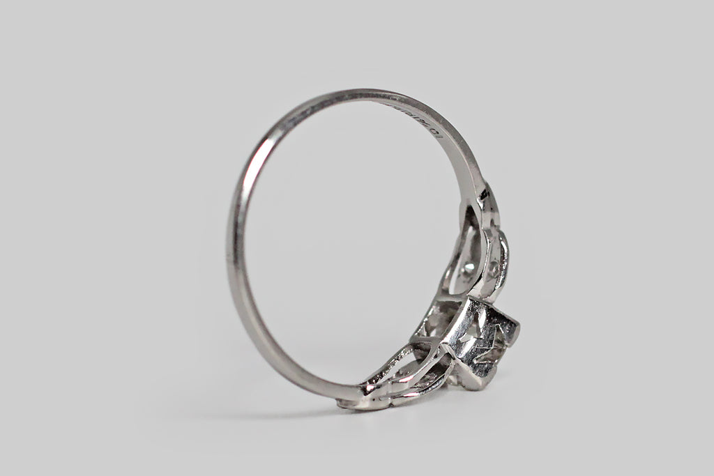 Poor Mouchette | Curated Antique Jewelry, Vintage Jewelry & Engagement Rings | Portland, Oregon | An elegant, mid 20th century engagement ring, modeled in platinum, whose primary gem is a .53 carat old European cut diamond (I/J, SI1). This sparkling, hand-cut sweetheart is mounted in a low-profile, four-tab basket setting— its "picture corner" style tabs are embellished with fine milgrain. This basket is hand-pierced with a simple chevron pattern, and is flanked