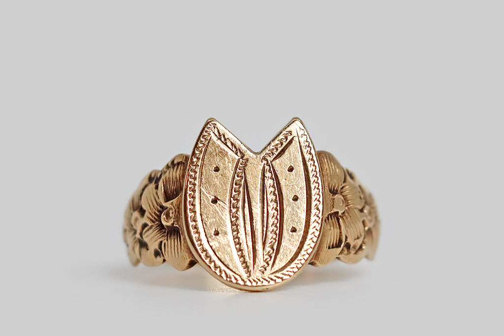 Poor Mouchette | Curated Antique Jewelry, Vintage Jewelry & Engagement Rings | Portland, Oregon | A wonderful, Victorian-era signet ring, modeled in 14k yellow gold, whose face is a lucky horseshoe! This horseshoe is deeply engraved, using both smooth and ropey lines. It is dotted with six nails, and is flanked by the lush, carved, flower garlands that decorate the ring’s shoulders. Our trios of flowers are overlapping and highly-dimensional— the outermost petals create the ring shank's scalloped edge.