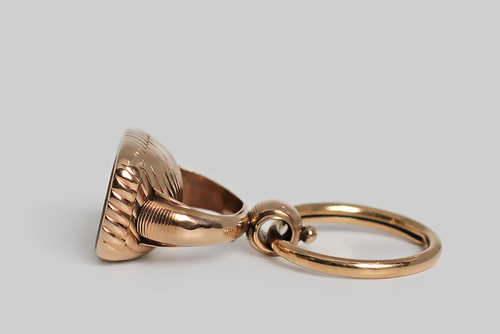 A wonderful, early-Victorian wax seal fob, modeled in 15k rose gold, whose bezel-set, agate (carnelian) seal features an intaglio carved rebus. This rebus puzzles out to mean: I hope you are well! An anchor was the popular symbol for hope during the Victorian era, and the tree in this diagram is a Yew tree. The fob itself is classically formed, with a broad stirrup-shaped arch, a round finial bail, and fine, hand-engraved lines, both straight and pinwheeling.