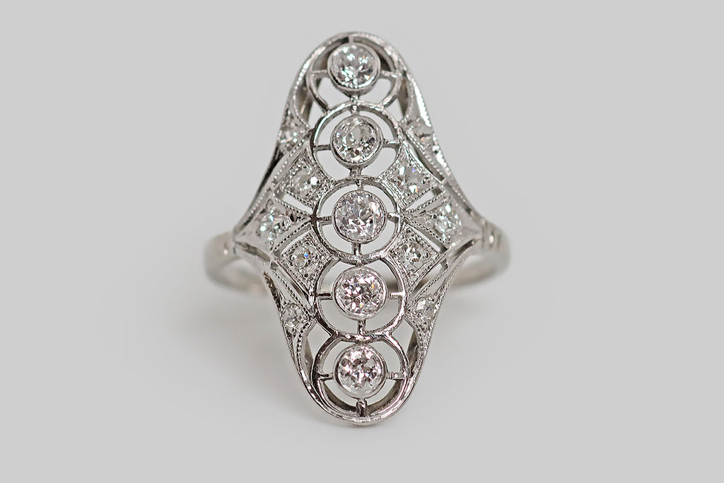 Poor Mouchette | Curated Antique Jewelry, Vintage Jewelry & Engagement Rings | Portland, Oregon | An elegant, Art Deco era, diamond cluster ring, modeled in platinum, whose softly-peaked, elongated form is reminiscent of a shield. This airy, openwork shield features five, bezel set diamonds (arranged vertically) that float inside hand-pierced, target-like fields. These five old European cut diamonds