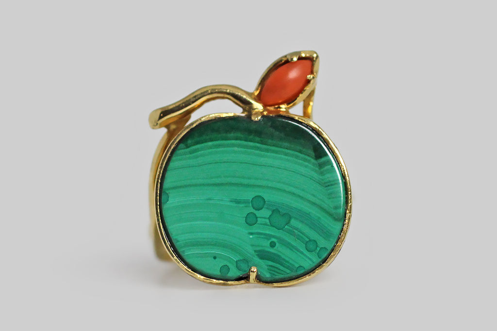 Poor Mouchette | Curated Antique Jewelry, Vintage Jewelry & Engagement Rings | Portland, Oregon | A playful, mid 20th century ring, modeled in 18k yellow gold, whose face takes the form of an apple. The body of this apple is a beautifully-figured, flush-set, polished, malachite slab. A small coral leaf perches atop the green fruit, alongside its curved, gold stem. This ring's low-profile setting is highly-structured and airy, with a bypass-style shank