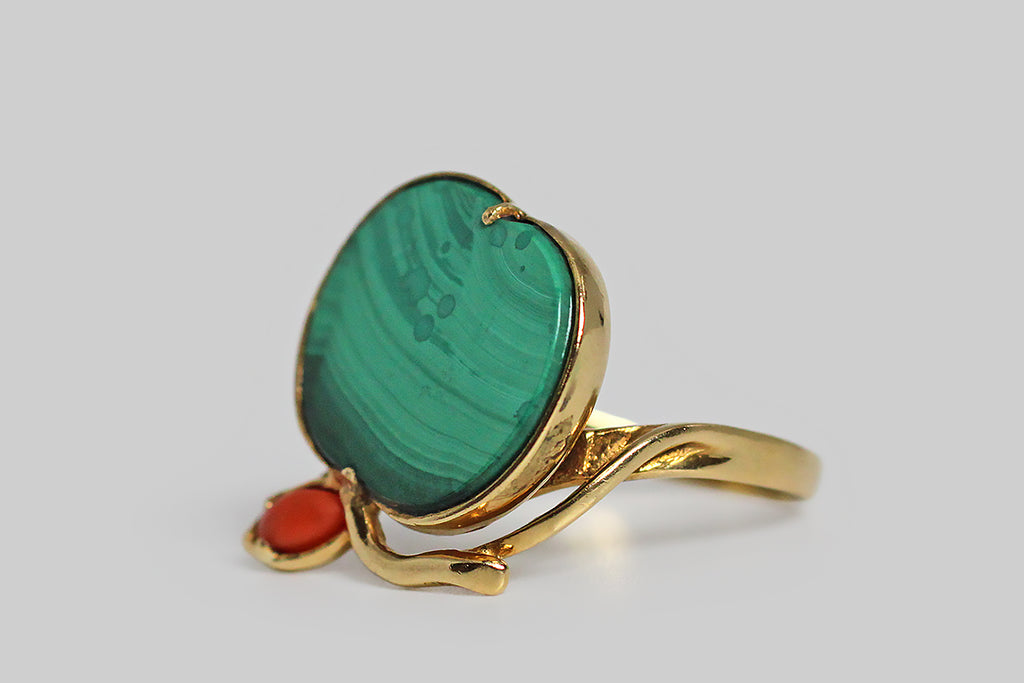 Poor Mouchette | Curated Antique Jewelry, Vintage Jewelry & Engagement Rings | Portland, Oregon | A playful, mid 20th century ring, modeled in 18k yellow gold, whose face takes the form of an apple. The body of this apple is a beautifully-figured, flush-set, polished, malachite slab. A small coral leaf perches atop the green fruit, alongside its curved, gold stem. This ring's low-profile setting is highly-structured and airy, with a bypass-style shank